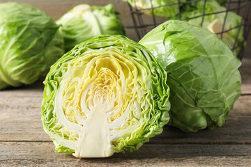 Fresh cabbages and basket on wooden table, closeup