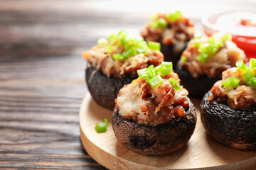 Delicious stuffed mushrooms and sauce on wooden table, closeup. Space for text