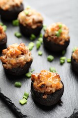 Tasty stuffed mushrooms served on black table, closeup