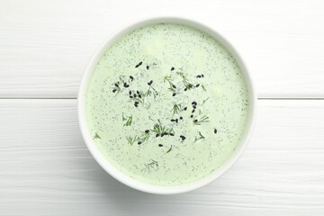 Tasty cucumber soup with dill and sesame seeds on white wooden table, top view