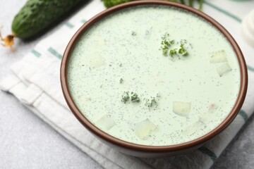 Tasty cucumber soup and ingredients on light grey table, closeup
