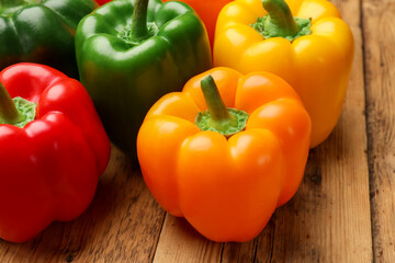 Fresh colorful bell peppers on wooden table, closeup