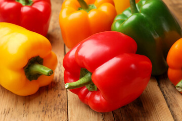 Fresh colorful bell peppers on wooden table, closeup