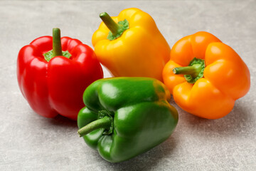 Fresh colorful bell peppers on gray textured table, closeup