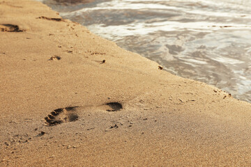 Footprint on sandy beach near sea, closeup