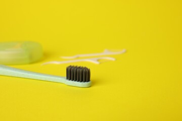 Toothbrush and floss picks on yellow background, closeup. Space for text