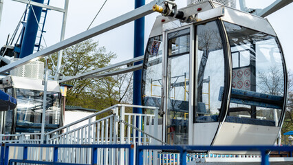Cable cars stand ready for adventure at an amusement park in springtime, inviting visitors to...