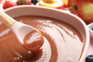 Baby food. Eating tasty puree with spoon at pink table, closeup