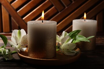 Burning candles and lily flowers on wooden table, closeup