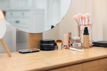 Different makeup products and brushes on vanity indoors, closeup