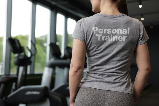 Personal trainer wearing t-shirt with inscription in gym, closeup. Back view