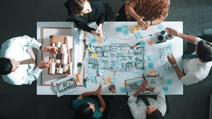 Top aerial view of manager shaking hand and making contract at meeting table with blueprint and house model. Group of diverse people working together and celebrate successful project. Alimentation.