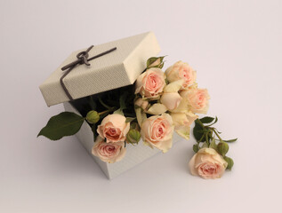 Craft gift box with beige cream rose flower bouquet on gray neutral background. Minimal empty...
