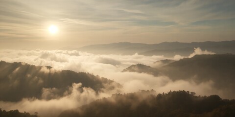 Fototapeta premium Aerial view of a misty mountain range at sunrise with clouds covering the valleys below horizon