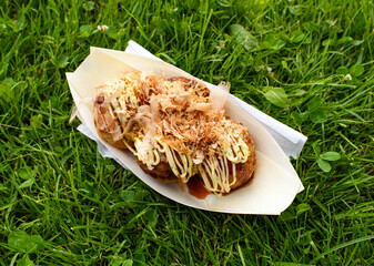 Takoyaki in a paper bowl on grass 