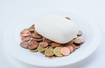Bar of white soap placed on euro cent coins scattered close-up financial hygiene concept