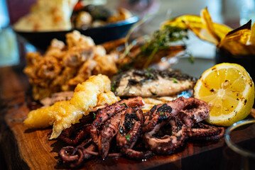 Set of seafood on wooden board, focus on octopus in foreground