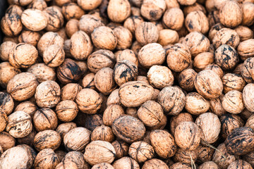 A large heap of natural unpeeled walnuts creates a rustic food pattern