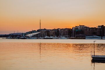 Bathed in the warm glow of sunset, Oslo harbour showcases traditional colourful wooden houses along...