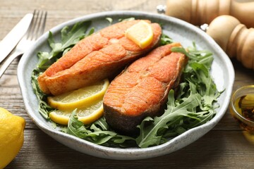 Seafood. Tasty salmon steaks served with arugula and lemon on wooden table, closeup