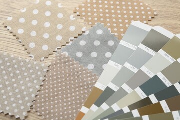 Samples of colorful fabrics and color palettes on wooden table, closeup