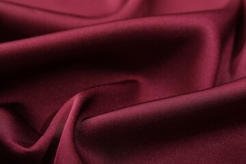 Crumpled burgundy silk fabric as background, closeup