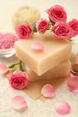Soap bars, sea salt, essential oil and beautiful roses on beige table, closeup