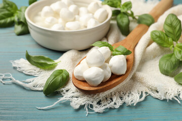 Mozzarella cheese balls and basil on blue wooden table, closeup
