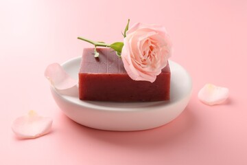 Soap bar and beautiful rose on pink background, closeup