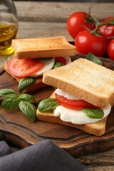 Tasty sandwiches with mozzarella cheese, tomatoes and basil on table, closeup