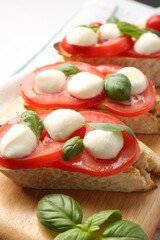 Tasty sandwiches with mozzarella cheese, tomatoes and basil on table, closeup