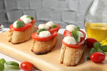 Tasty sandwiches with mozzarella cheese, tomatoes and basil on white table, closeup