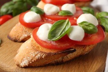 Tasty sandwiches with mozzarella cheese, tomatoes and basil on table, closeup