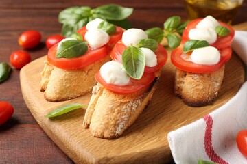 Tasty sandwiches with mozzarella cheese, tomatoes and basil on wooden table, closeup