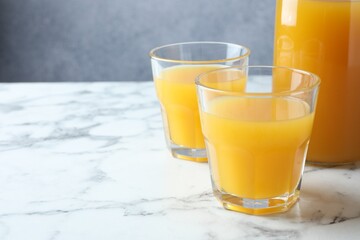 Tasty mango juice in glasses on white marble table, closeup. Space for text