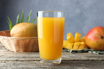 Tasty mango juice in glass and fresh fruits on wooden table