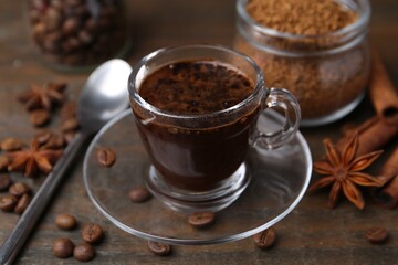 Cup of aromatic coffee, beans, instant powder and spices on wooden table, closeup