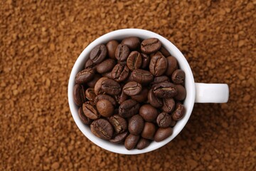 Cup of roasted beans on granulated instant coffee, top view