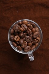 Cup of roasted coffee beans on powder, top view