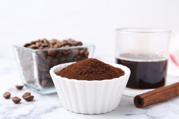 Instant coffee powder in bowl, beans and drink on white marble table, closeup