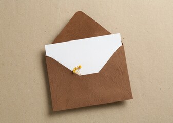 Blank invitation card with flowers and envelope on carton, top view