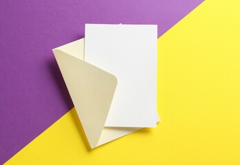 Blank invitation card and envelope on color background, top view. Space for design