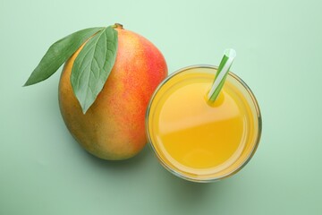 Tasty mango juice in glass and fresh fruit on green background, flat lay