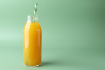 Tasty mango juice in glass bottle on green background, space for text