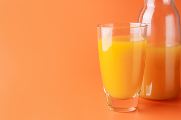 Tasty mango juice in glass and carafe on orange background, closeup. Space for text