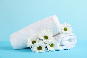 Soft towels and chrysanthemum flowers on light blue background