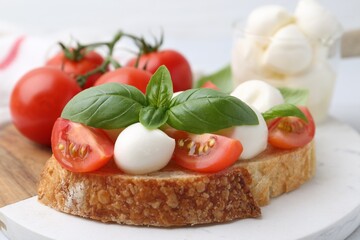 Tasty sandwich with mozzarella cheese, tomatoes and basil on table, closeup