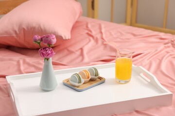 Tray with delicious breakfast and flowers on bed indoors, closeup. Space for text