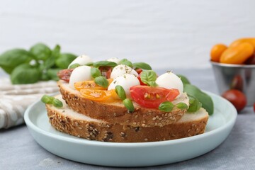 Tasty sandwich with mozzarella cheese, tomatoes and basil on grey table, closeup