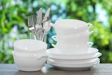 Different clean dishes on wooden table against blurred green background